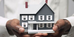 A person holding a model of a house. 