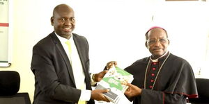PS Julius Bitok (left) hands over copies of Digital ID FAQ booklet to Kenya Conference of Catholic Bishops Chairman Archbishop Martin Kivuva.