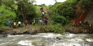 Curious onlookers attracted to the scene of an accident which claimed the jives of five relatives who were returning to Nairobi on Saturday night after attending a funeral of a relative in Meru at the Nyamindi river bridge, Kirinyaga County on May 24, 2015.