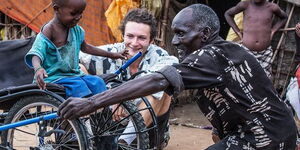Janna Deeble (centre) a wheelchair designer, shares a light moment with a child and physically challenged man in Samburu on October 26, 2016.