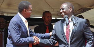 File photo of Cabinet Secretary for Tourism Alfred Mutua as he shakes hands with President Wlliam Ruto at an event 