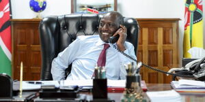 President William Ruto smiling while on call in his office.