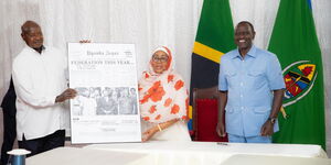 President Yoweri Museveni (Uganda) presenting a photo to President Samia Suluhu (Tanzania) at a meeting in Zanzibar on March 14, 2024, as President William Ruto (Kenya) onlooks. 