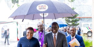 President William Ruto (right) holds the umbrella for Health CS Susan Nakhumicha while making their way to Syokimau, Machakos County on November 22, 2023. 
