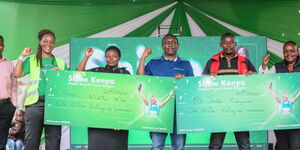 From left Mr Mutua Ndungi Image Connections – Safaricom Dealer, Esther Waititu Chief Financial Services Officer at Safaricom Safaricom , winner of one million Mrs Naomi Mbithe, Mr Jackson Mutua Regional Business Lead at Safaricom, Mr Jackson Habagusaba and Miriam Chesaina Territory Business Lead Safaricom pose for a photo with a dummy cheque during the week three winners announcement of Shinda Mamilii Kama Bingwa campaign in Machakos County.