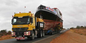 A photo of a boat being transported on a highway.