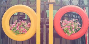 A tyre garden of plants suspended on a gate.