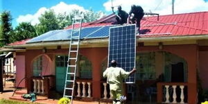 A photo of electricians installing solar panels in a house in Kenya.