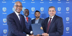 Dr. Joshua Oigara, Chief Executive, Stanbic Bank Kenya and South Sudan exchange documents with Anoop Gala, Global Head of Financial Services, Orion Innovation during a software agreement signing ceremony. Looking on is Alex Siboe (Standing left) Head of Technology, Stanbic Bank Kenya and Mustajab Ali, Director, Business Development, Banktech (MEA).