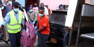 Police officers transfer a body from a house in Kericho County. 