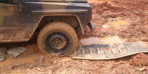 An off-road vehicle uses a traction mat to get out of mud.  