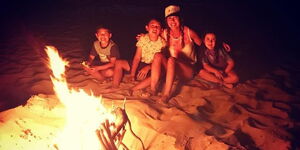 Photo of a family passing time around a bonfire at night