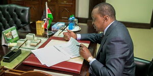 President Uhuru Kenyatta reading documents in his office