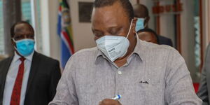 President Uhuru Kenyatta signing a ball after meeting with leaders from Western Kenya on July 1, 2020.
