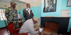 President Uhuru Kenyatta signs the visitor's book inside the historic Kenyatta house on Friday, March 5, during his visit