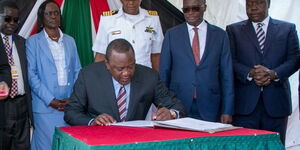 President Uhuru Kenyatta(Seated) signing a book ahead of SGR freight train launch in Nairobi. Behind the president are from right Interior CS Fred Matiang'i and Transport CS James Macharia.