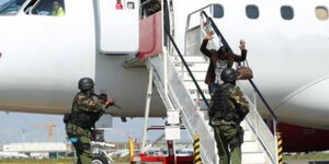 A photo of a plane passenger lifting her hands as a sign of surrender to police officers.