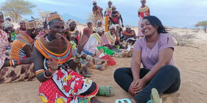 Beldeen Waliaula (right0 interacts with a group of women during the filiming of  a past story. 