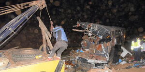 A breakdown vehicle prepares to tow away the wreckage of the bus that collided head-on with a 14-seater matatu on the Meru-Nanyuki road on October 8, 2022.