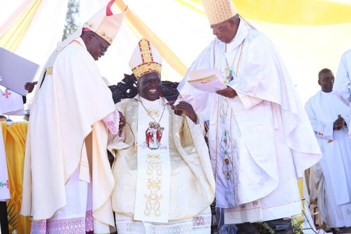 Bishop Philip Anyolo (center) is throned during a consecration at Uzima University grounds as an Arch Bishop of the Kisumu Arch-Diocese by Bishop Zacheous Okoth (left) and John Cardinal Njue. 