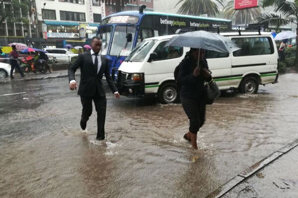 Pedestrians wade floodwater in the city centre on March 15, 2018. Kenya Met Department warned that there will be a heavy downpour in parts of the country