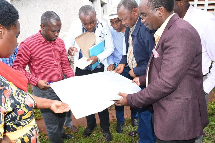 The team that visted the Kirwara hospital on October 22 look at the plans on the construction of the hospitals.