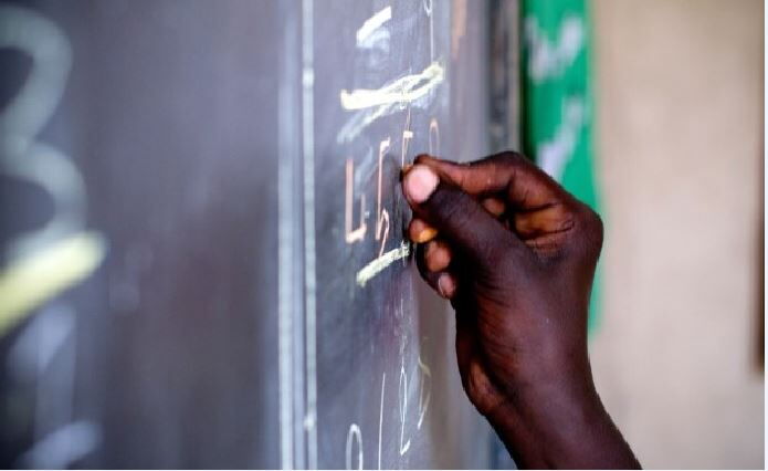 image of teacher's hand writing on the blackboard