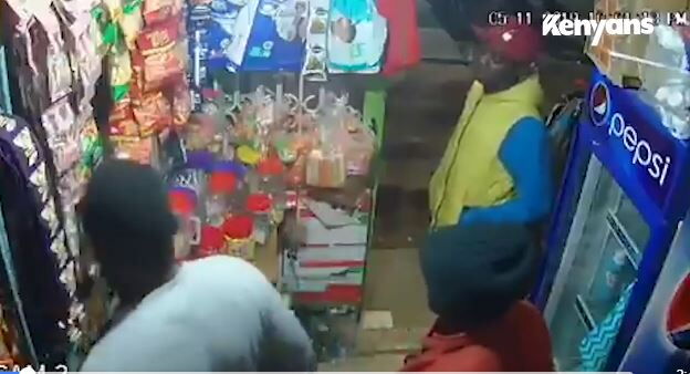 A screen grab of the CCTV yfootage showing the thug (one in a yellow jacket and the other in a black marvin) and the customer in a grey shirt