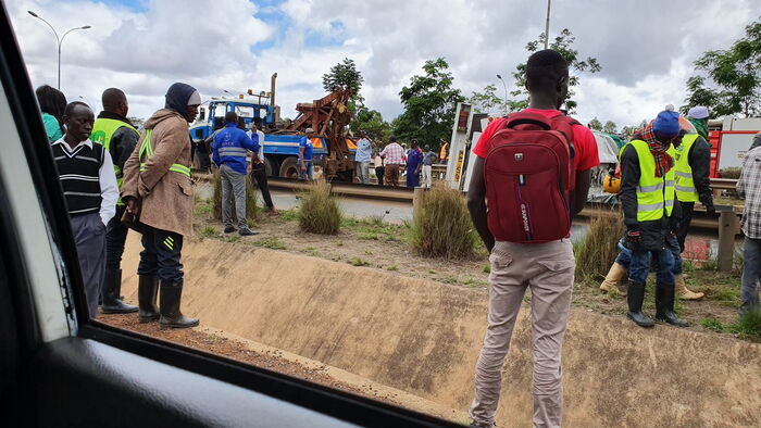 Locals standing next to an overturned oil tanker on Thika road.