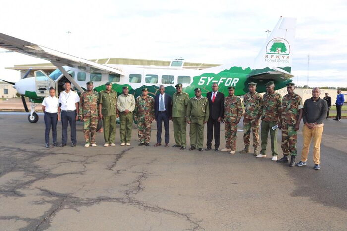 Eliud Kipchoge (centre) poses for a photo with his coach Paul Sang and a Kenya Forest Services (KFS) official after landing in Mombasa on October 19, 2019.