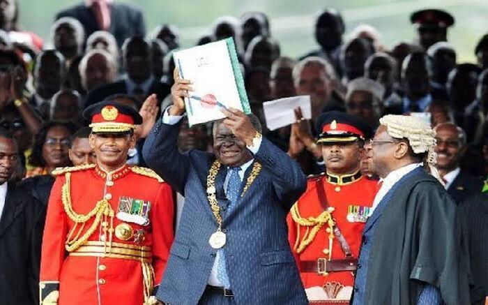 Former president Mwai Kibaki holds up the Kenyan Constitution on August 27, 2010.
