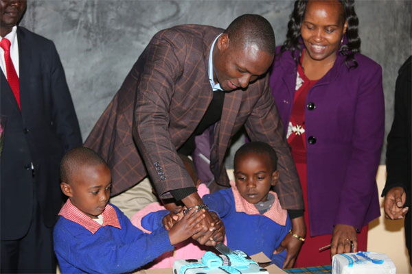 Kajiado Deputy Governor Martin Moshisho and pupils of Upper Matasia Primary School cut a cake after launching a new ECDE complex at the school on July 12, 2018.