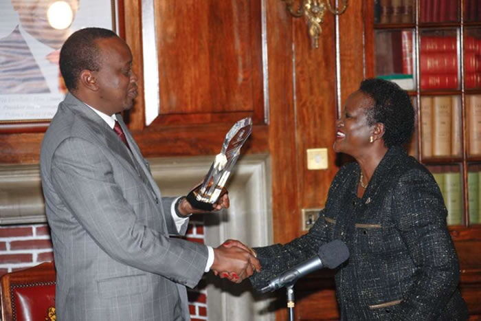 President Uhuru Kenyatta handing a trophy over to his sister Kristina Pratt. She was Jomo Kenyatta's firstborn child, followed by President Uhuru Kenyatta.