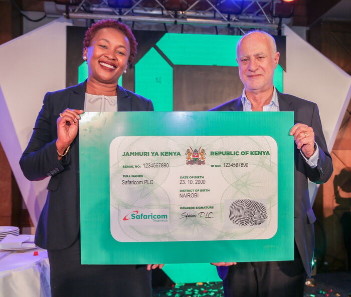 Sylvia Mulinge and the Safaricom CEO Michael Joseph hold up a dummy ID card during Safaricom's 18th birthday on October 22, 2018.