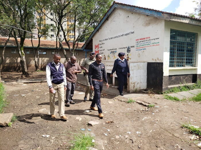 Police officers escort Boniface Mwangi and a group of activists as they reclaimed a section of Racecourse Primary school that had been grabbed, November 20, 2019.