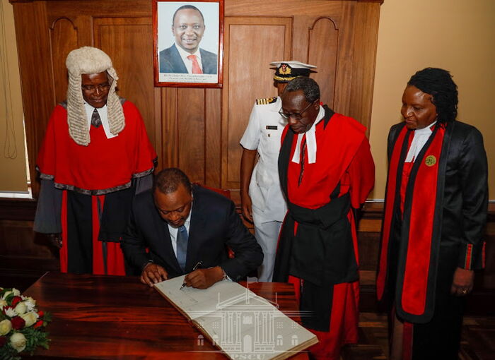 President Uhuru Kenyatta signs the guest book at the Supreme Court as senior Judicial officers look on led by Chief Justice David Maraga on Thursday, January 23, 2020