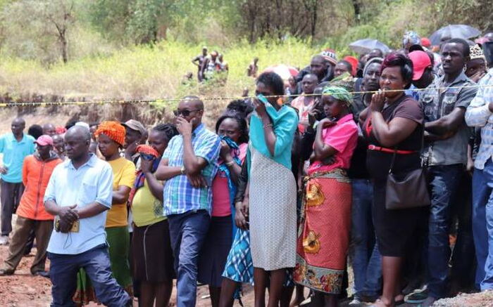 Residents watch the exhumation of the body of murdered priest Father Michael Kyengo.