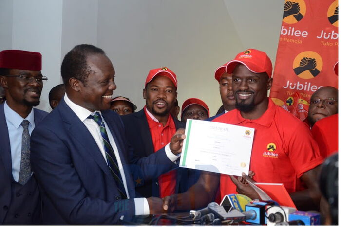 Jubilee Secretary-General Raphael Tuju awarding Dennis Itumbi with nomination certificate. Itumbi's defence of Mariga after he was barred from contesting backfired on him