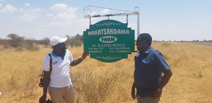 Willy Kathurima (r) poses alongside the road signage leading up to his ranch in Botswana.