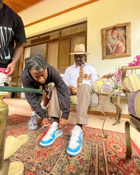 Young Designer Ali helping Raila Odinga fit into his shoes at his Karen Home on June 12