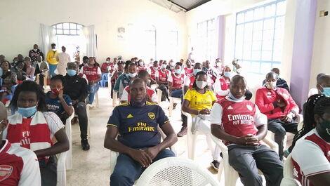 A photo of Arsenal fans seated in a hall.