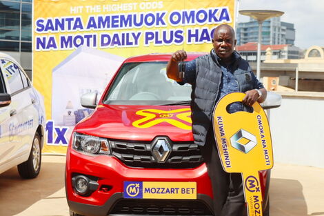 An image of one of the lucky winners of Mozzart Bet's Omoka na Moti promotion posing with his new car.