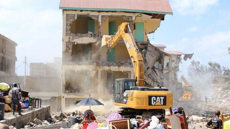 A bulldozer pulling down a house