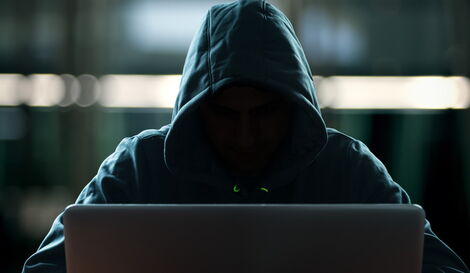Undated file image of an individual with a hidden face working on a computer.