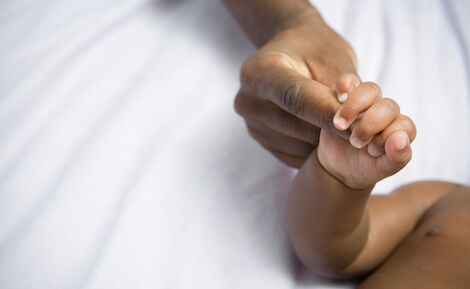 A mother holding her child's hands in hospital.
