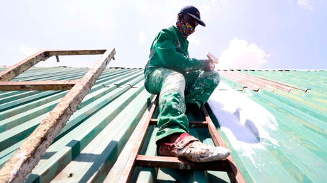 A person applying the reflective coat on a roof
