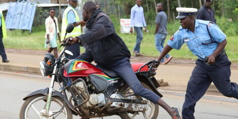 A police officer attempts to arrest a bodaboda rider