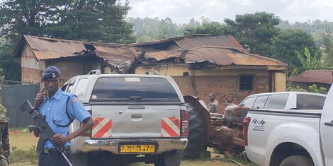 A police officer makes a call at the scene of the arson in Kandara, Murang'a.