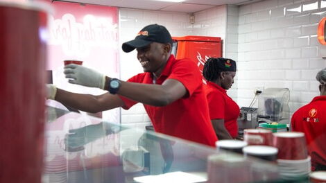 An attendant serving a customer at the newly opened Domino's and Coldstone outlet