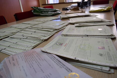 A file image of Kenya National Examination Council certificates on a table.